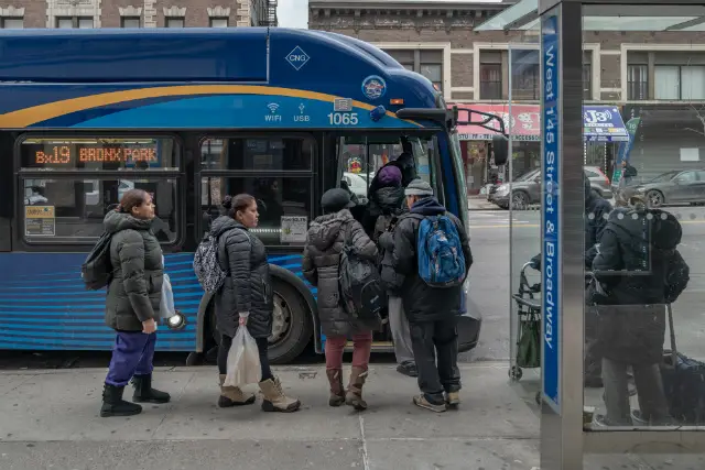 Commuters board an MTA BX19 bus after waiting over 15 minutes for the bus to arrive.